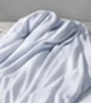 연한 하늘색 냉감 이불이 덮인 침대
