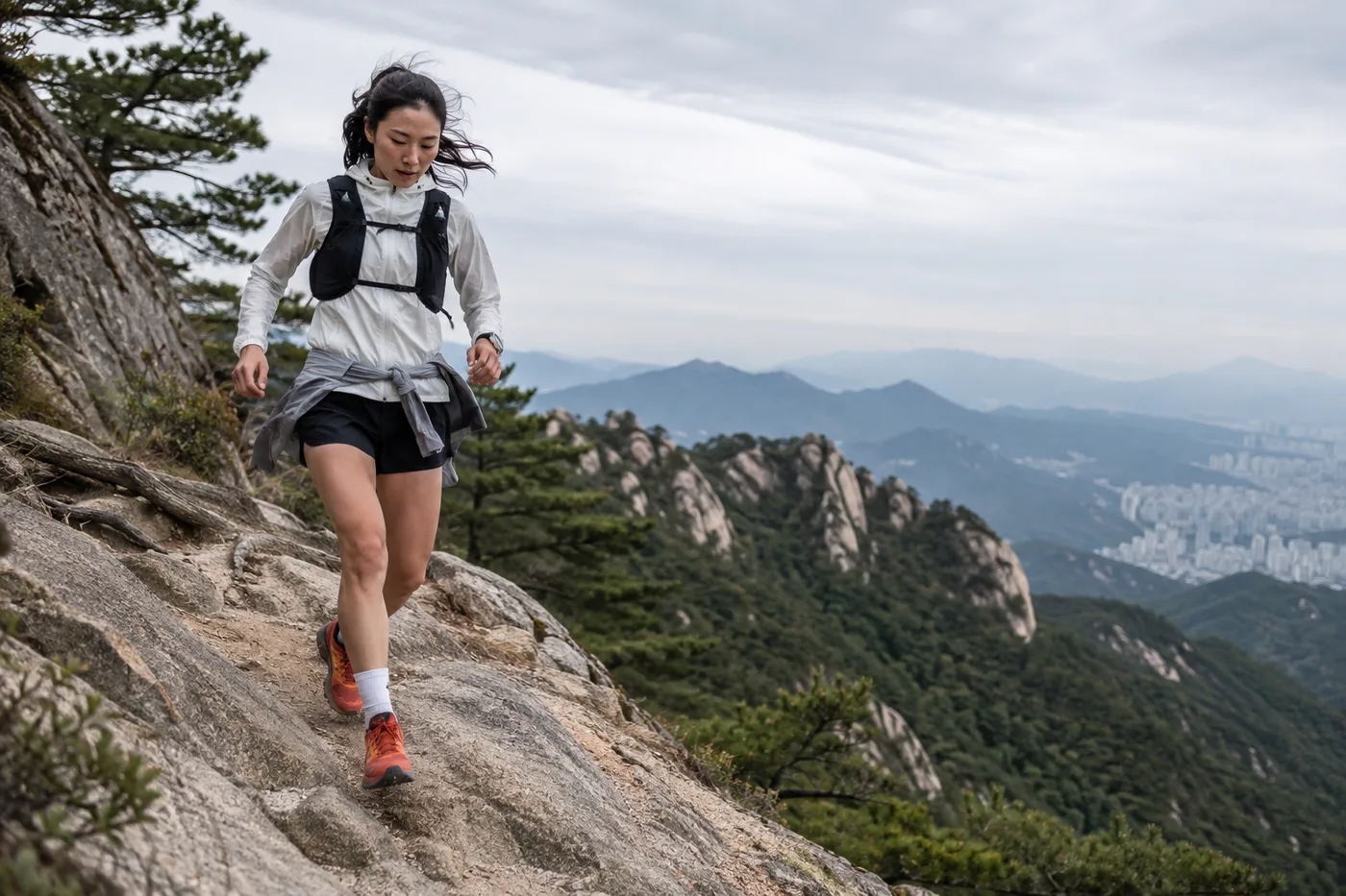 A trail runner descending a rocky ridge above the city