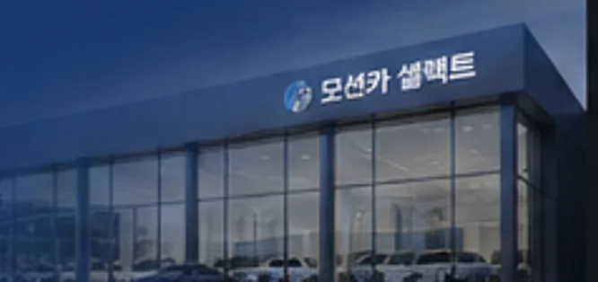 모션카 셀렉트 강남 전시장 외관. 유리 파사드 뒤로 전시 차량이 보입니다.