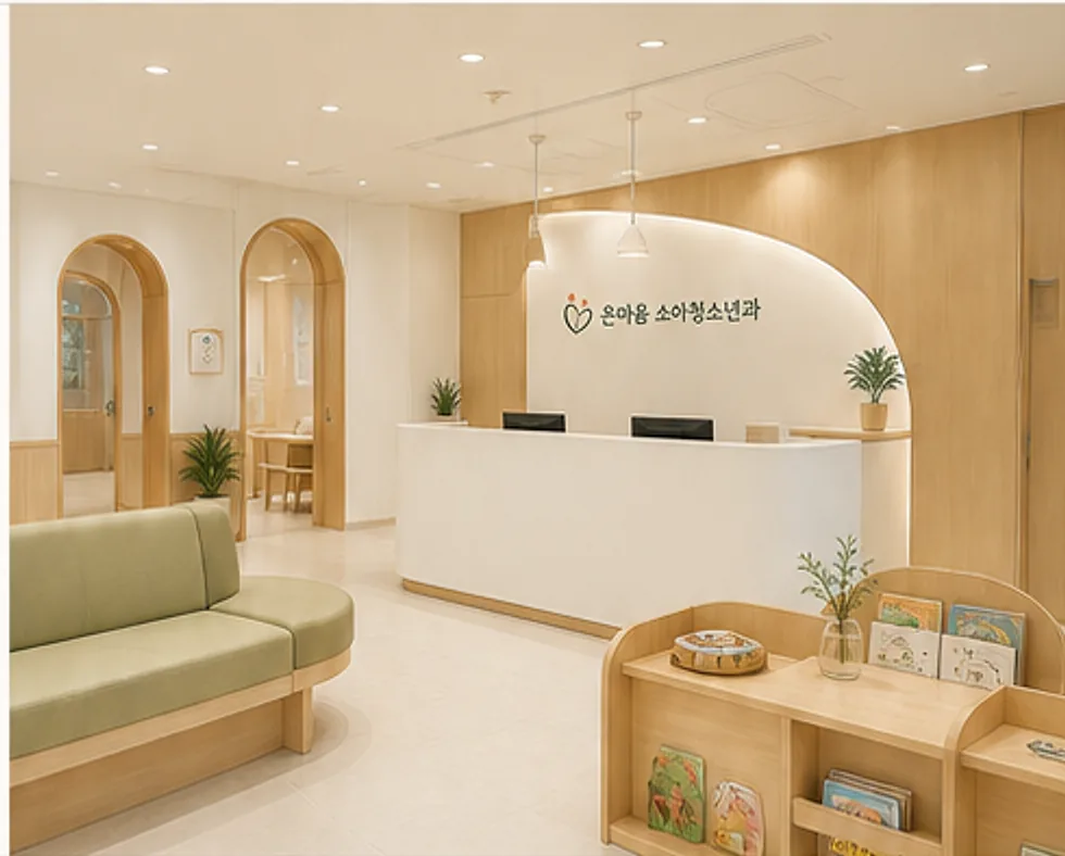 원목과 초록빛 소파로 꾸민 온마음 소아청소년과 접수 데스크와 대기 공간