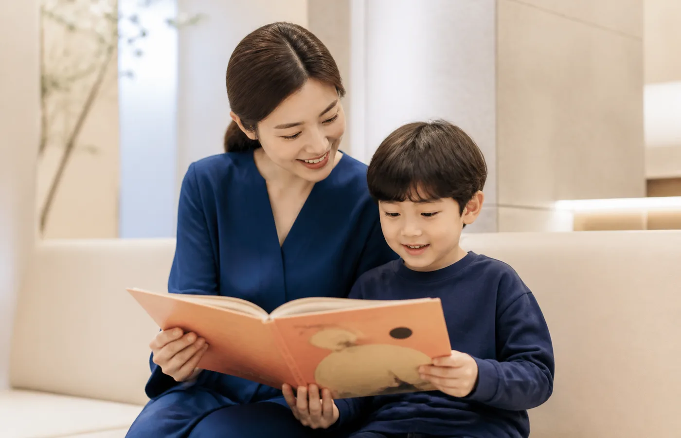 밝은 대기 공간에서 책을 읽는 가상의 한국인 보호자와 아이